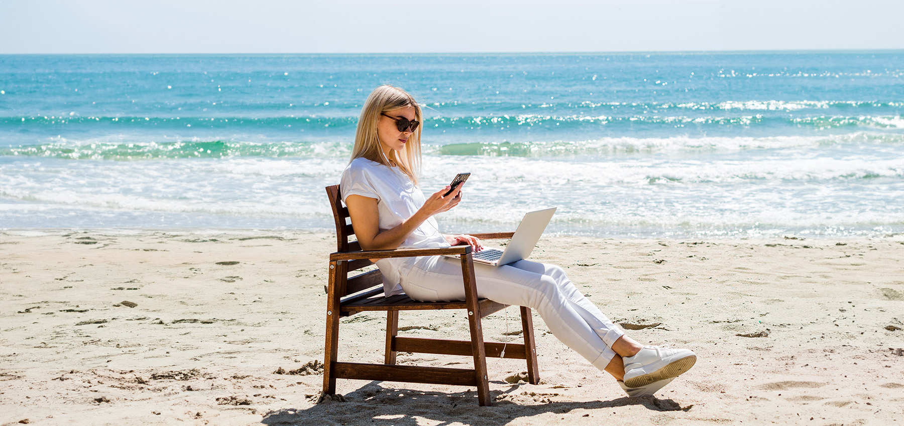 mujer en la playa utilizando app móvil  para la gestión de marketing en vacaciones